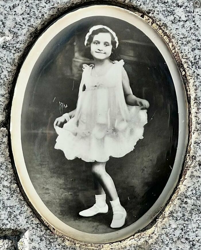 Old-fashioned headstone portrait of a young girl in a dress, adding a lovely touch to the memorial stone.