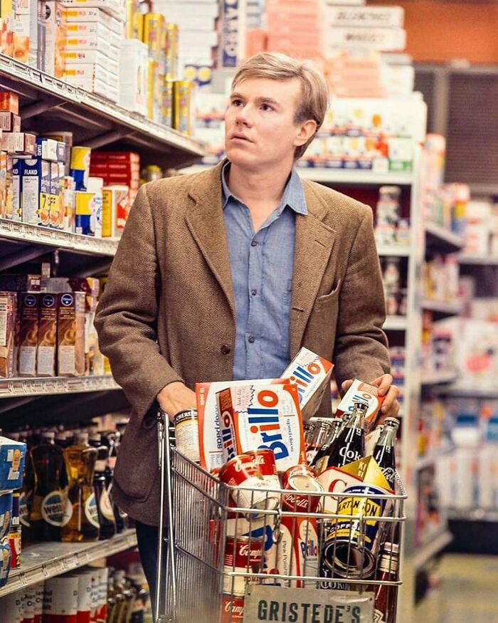 Man with a shopping cart in a supermarket, holding Brillo boxes, providing a historical look into past consumer habits.