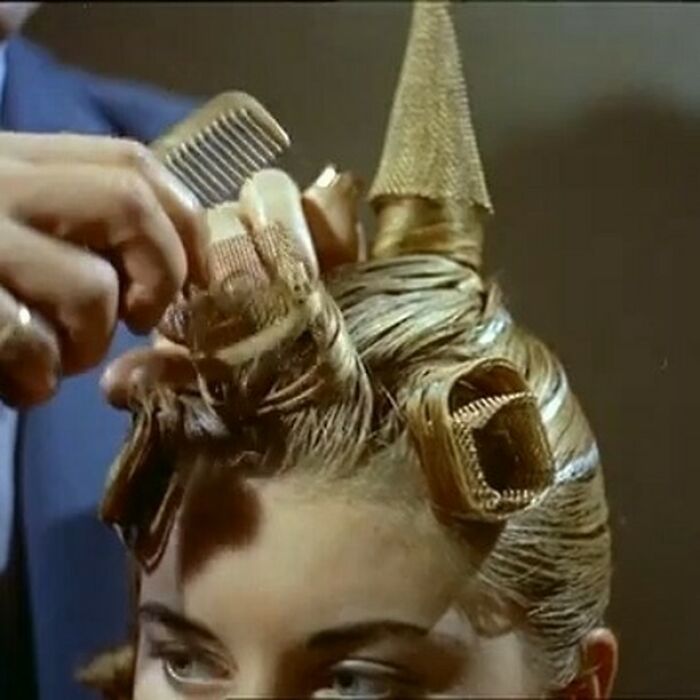 A stylist uses a comb on intricate historical hair rollers for a vintage hairstyle.
