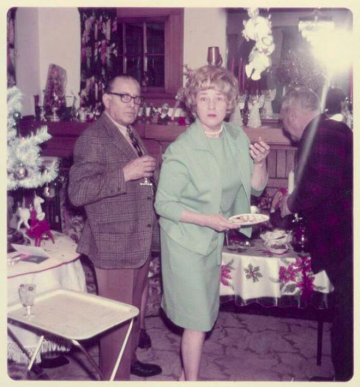 Vintage party scene with two people, one holding a drink, the other with a plate, capturing a historical moment from the past.