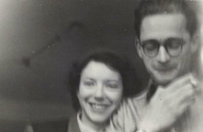 A historical photo of a smiling woman and a man with glasses, offering a glimpse into the past.