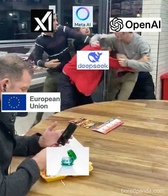 Work-related humor meme showing a chaotic scene with company logos and a man focused on his phone.