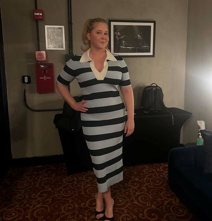 Celebrity in a striped dress poses confidently, showcasing a classy style in an elegant setting.