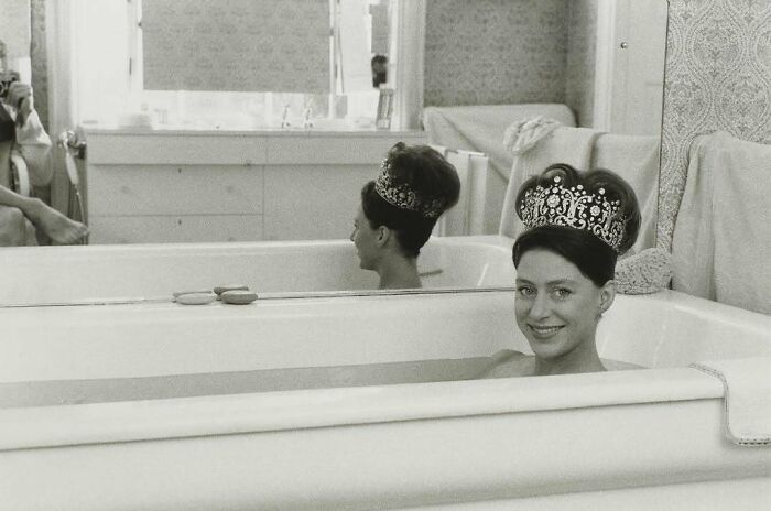 Woman in a bathtub wearing a crown, reflecting historical moments from the past.