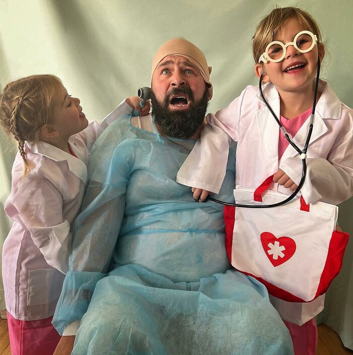 Dad in costume with daughters dressed as doctors, creating a funny and adorable family moment.