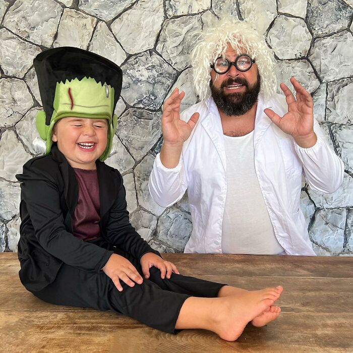 Dad in a white wig and lab coat, with daughter dressed as Frankenstein, sharing a fun costume moment.
