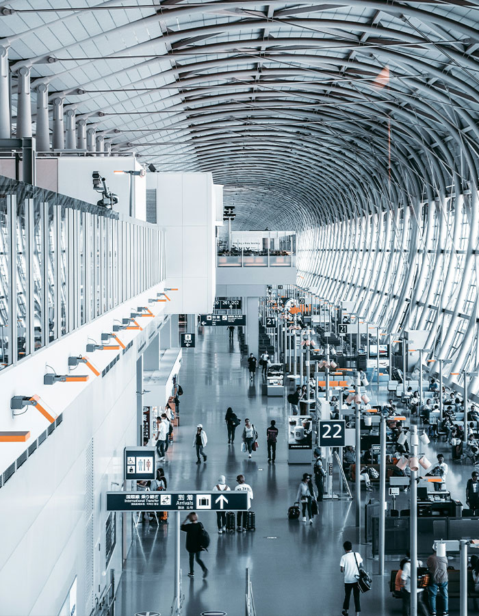 Crowded airport terminal with passengers walking and signs indicating gates, creating a bustling travel environment.