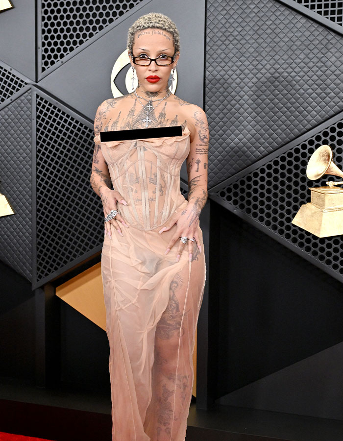 Person in a sheer gown with tattoos, at an event, highlighting cultural moment in debate over pubic hair.