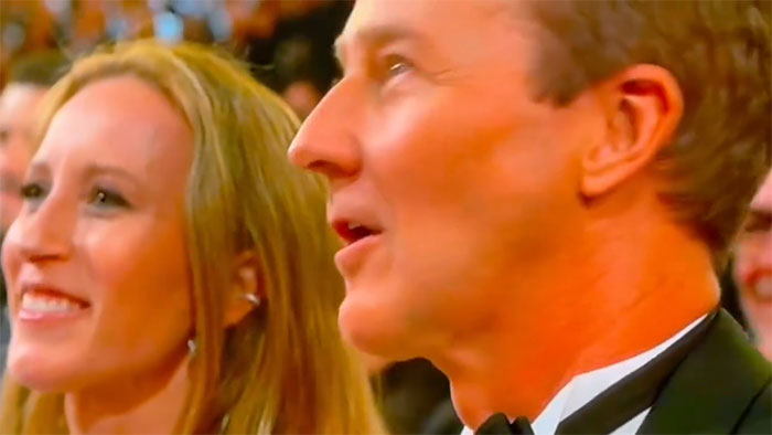 Edward Norton shows surprise in a black tuxedo at the Oscars, reacting during the live ceremony.