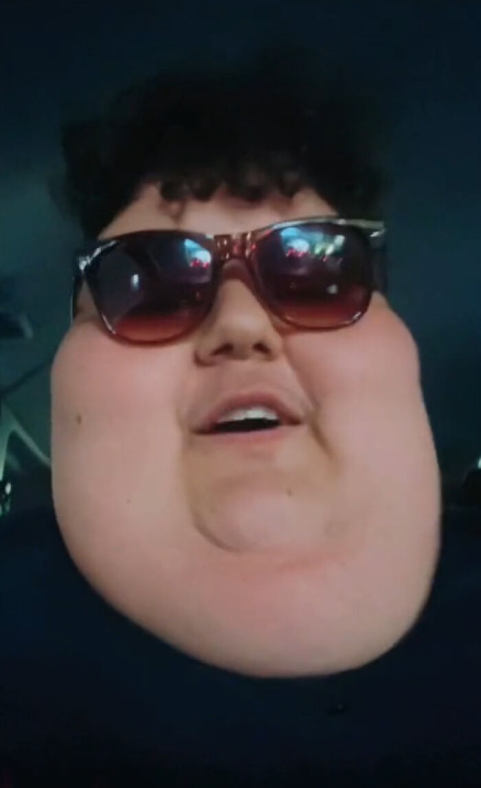 Person wearing sunglasses, known for viral mukbang videos, shown smiling. Person wearing sunglasses, known for viral mukbang videos, shown smiling.