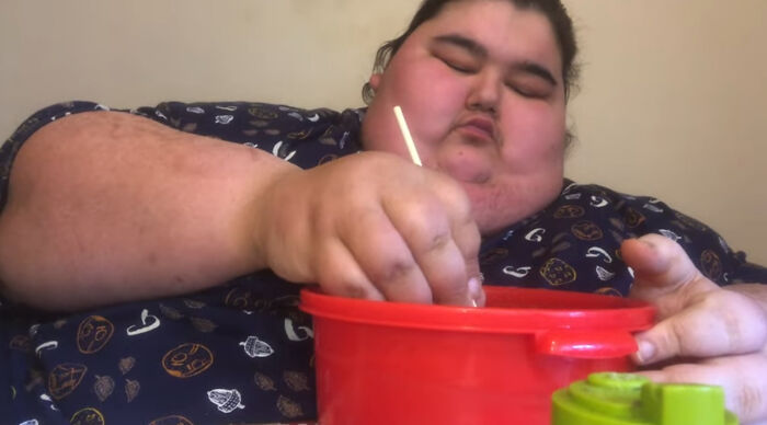 Person eating from a red bowl, known for viral Mukbang videos, associated with obesity-related health concerns. Person eating from a red bowl, known for viral Mukbang videos, associated with obesity-related health concerns.