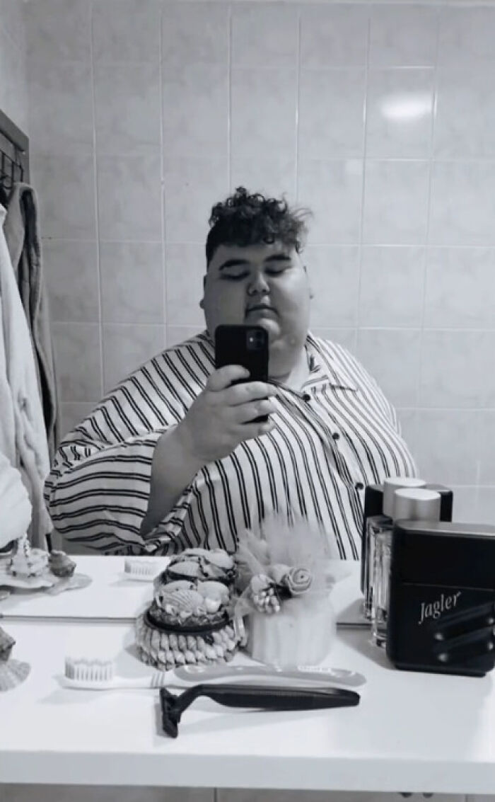 Extreme eater taking a mirror selfie in a striped shirt, standing in a bathroom. Extreme eater taking a mirror selfie in a striped shirt, standing in a bathroom.