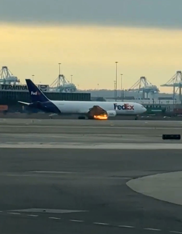 FedEx aircraft on runway with fire visible, indicating packages delayed after mid-air incident.