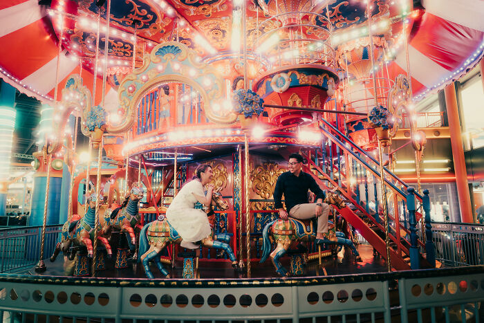 Couple on a colorful merry-go-round, capturing one of the best engagement photos of 2025 with vibrant lights and joyful expressions.