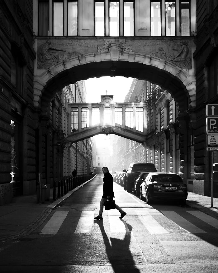 A man crossing the street in a black-and-white cityscape.