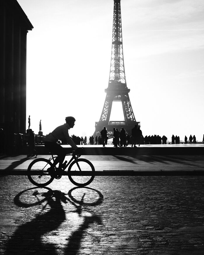 Black-and-white street photograph of a cyclist silhouetted against the Eiffel Tower.