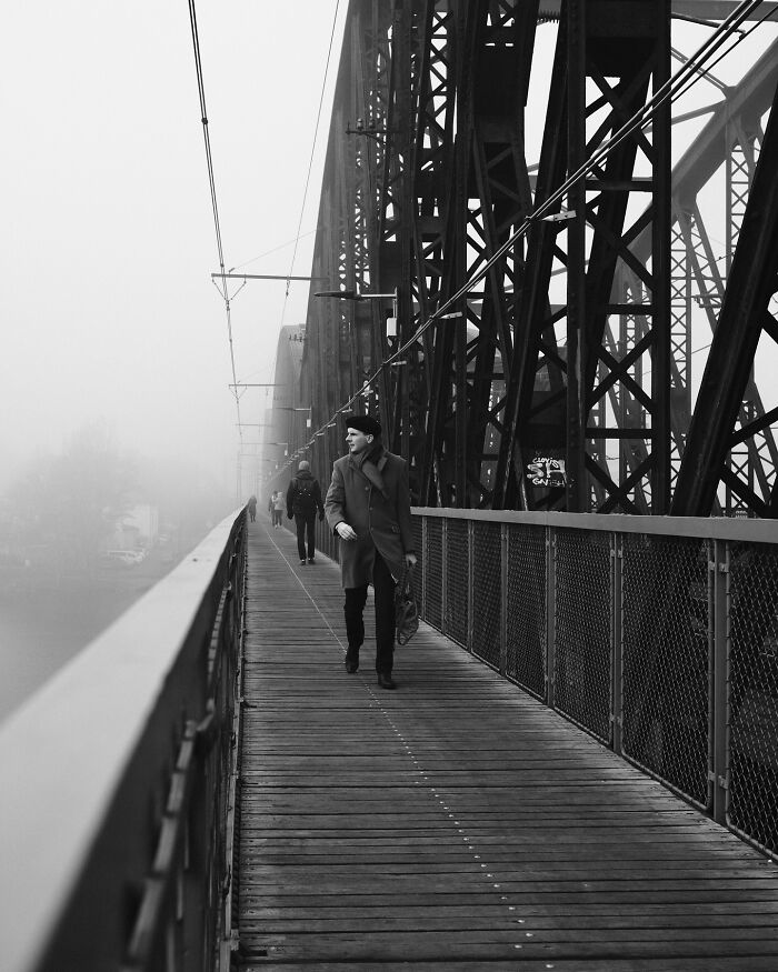 Person walking on a foggy bridge, a captivating black-and-white street photograph by Fernando Pedro Salgado.
