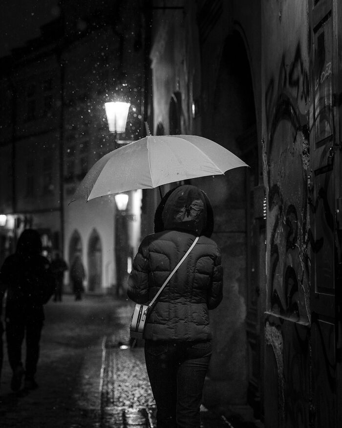 Person with umbrella walking at night, showcasing black-and-white street photography by Fernando Pedro Salgado.