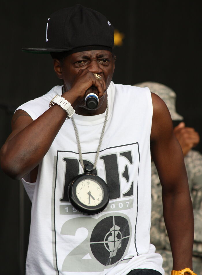 Rapper with clock necklace performing on stage, capturing a funny celebrity interaction moment.