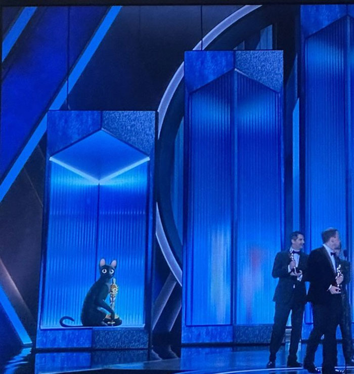 Oscar winners 2025 on stage with trophies, alongside a blue illuminated backdrop.