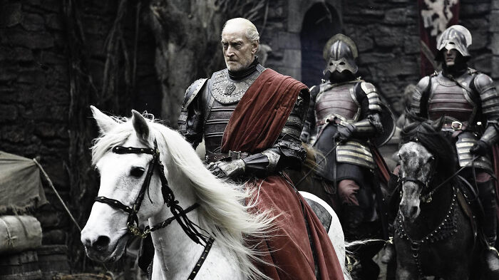 Actor in medieval armor on a white horse, with soldiers in the background, embodying a role perfectly suited for them.