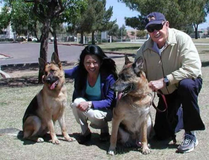 Man, woman, and two German Shepherds in a park, smiling. Man, woman, and two German Shepherds in a park, smiling.