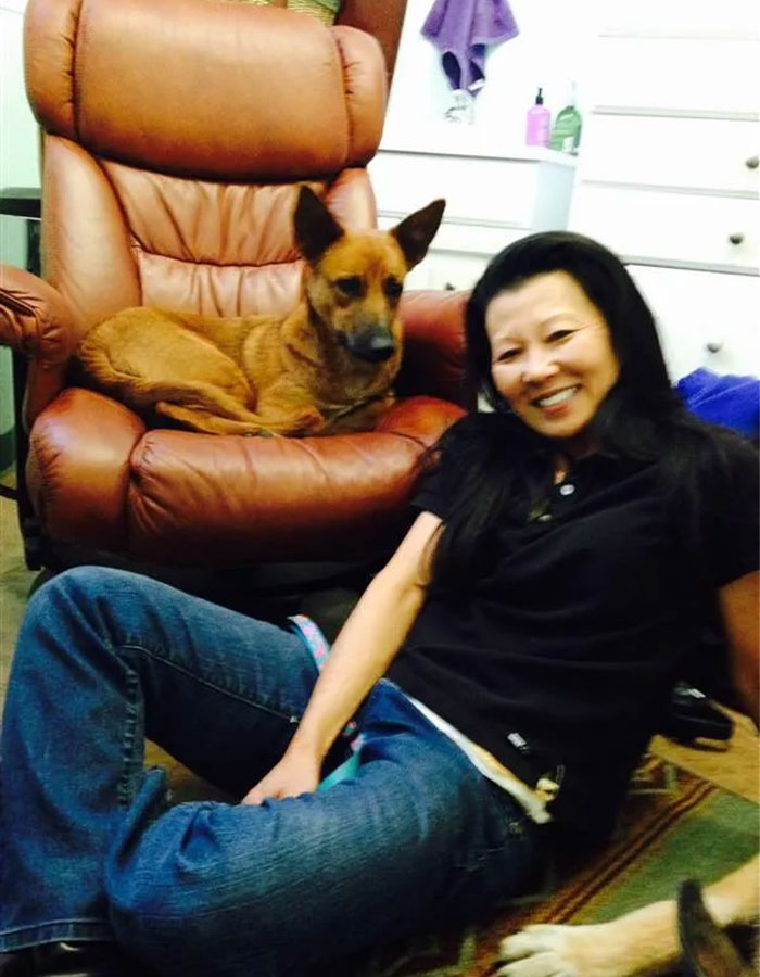 Woman smiling next to a dog on a leather chair, representing Gene Hackman's daughter's heartfelt moment. Woman smiling next to a dog on a leather chair, representing Gene Hackman's daughter's heartfelt moment.