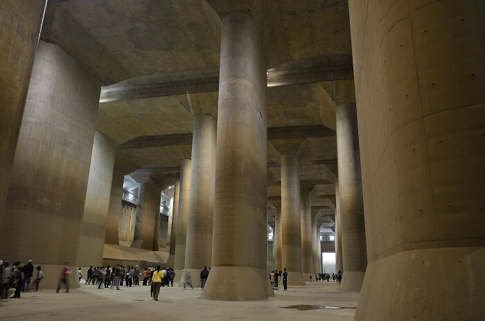 Massive underground space with iconic concrete pillars and small groups of people exploring.
