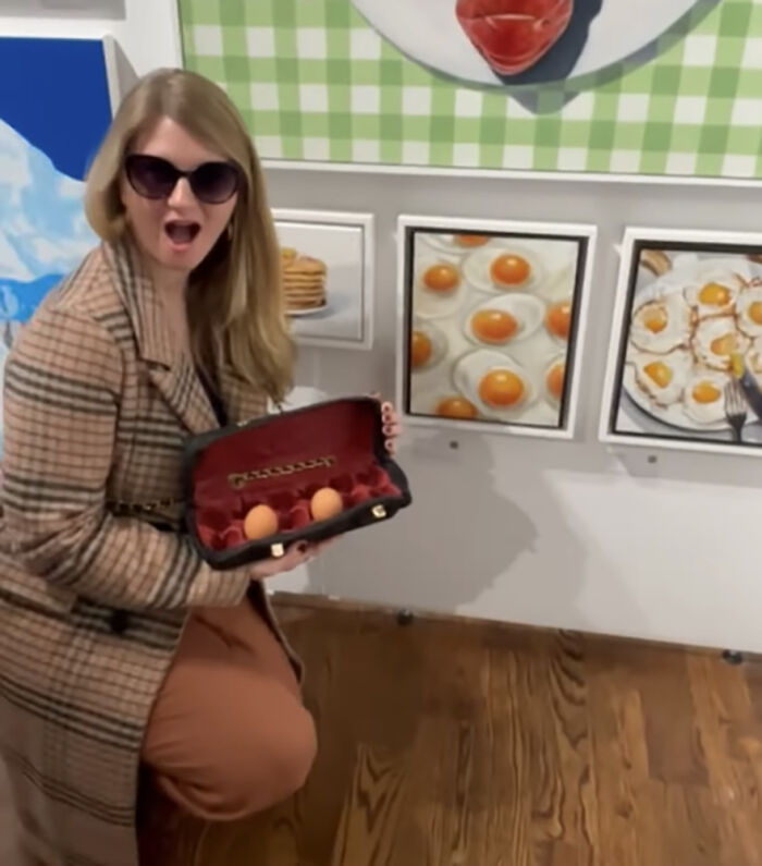 Woman holding a luxury handbag designed to carry eggs, illustrating commentary on high prices. Woman holding a luxury handbag designed to carry eggs, illustrating commentary on high prices.