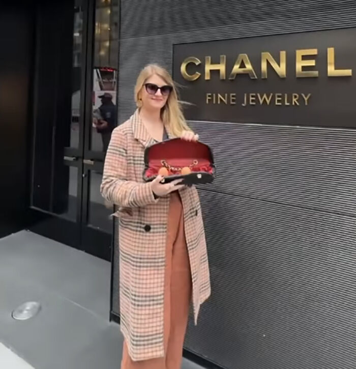 Person holding luxury handbag designed for eggs outside Chanel store, illustrating high prices commentary. Person holding luxury handbag designed for eggs outside Chanel store, illustrating high prices commentary.