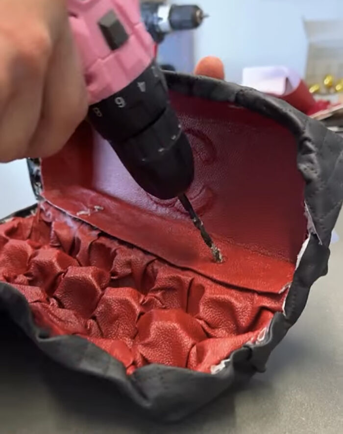 Close-up of a luxury handbag being crafted, featuring a drill and red leather for carrying eggs, commenting on high prices. Close-up of a luxury handbag being crafted, featuring a drill and red leather for carrying eggs, commenting on high prices.