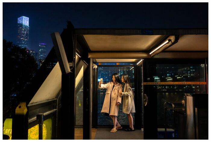 Two women taking a selfie in a city setting at night, capturing unfiltered street moments.