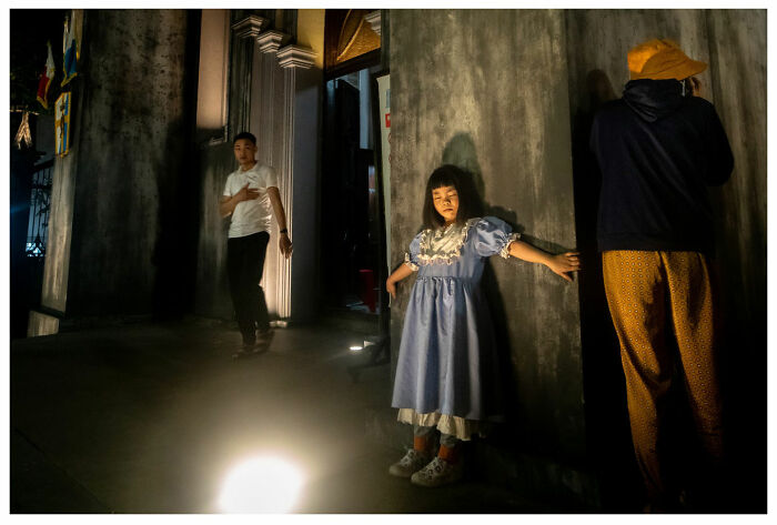 Street photography showing three individuals in contrasting light and shadow, depicting a dramatic urban scene.
