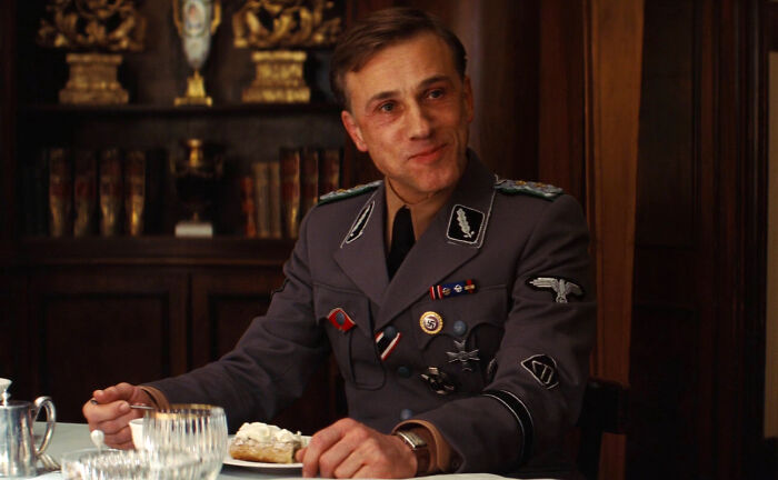 Actor in a WWII military uniform at a dining table, known for a role uniquely fitting them.