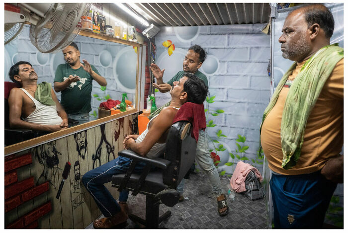 Barber shop scene captured by Andrés Ramos, showing raw, unfiltered moments with patrons and barbers in conversation.
