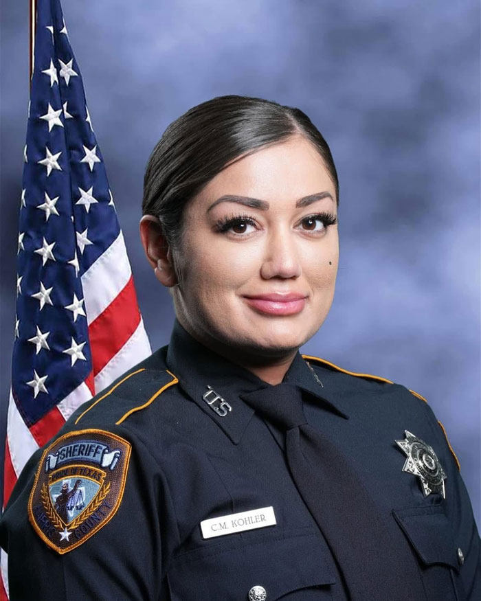 Texas deputy in uniform poses in front of American flag.