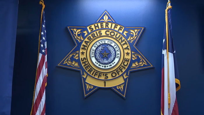 Harris County Sheriff's Office emblem on a blue wall with Texas and American flags.