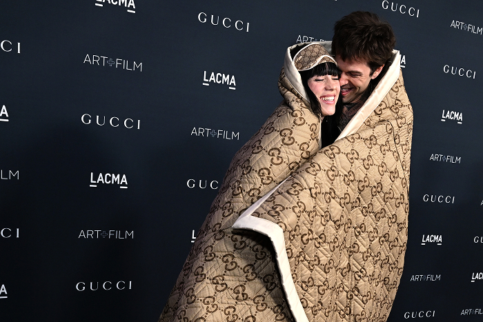 Billie Eilish and Jesse Rutherford wrapped in Gucci blanket at an event, relating to Billie Eilish dating rumors.