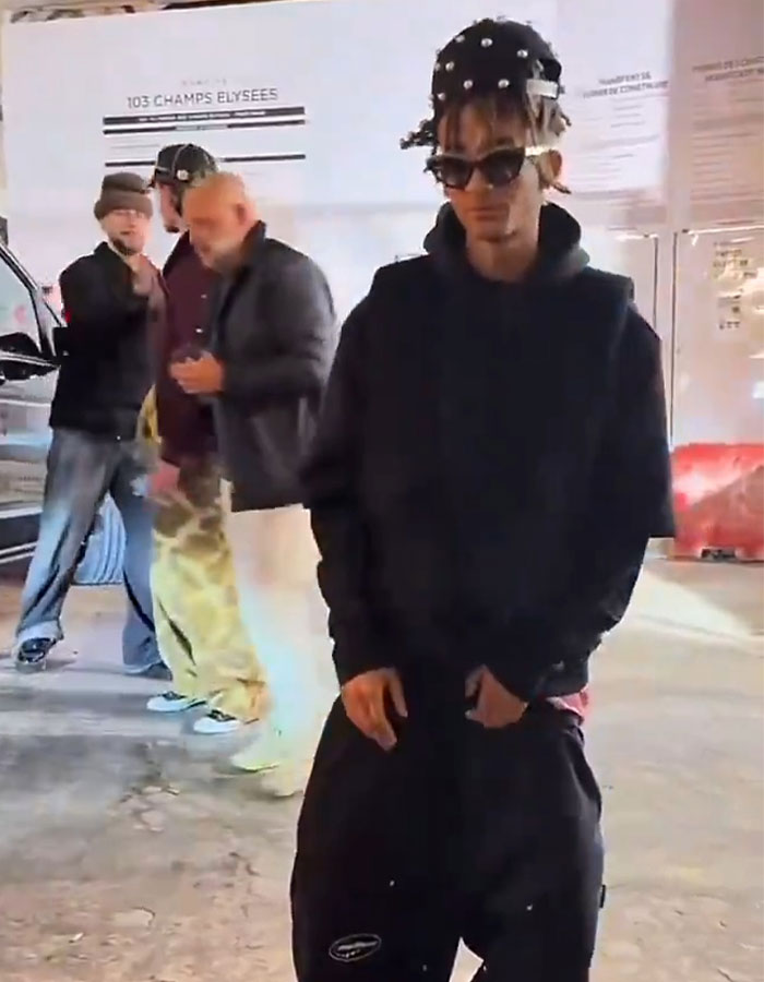 Teen in streetwear with unique hairstyle, standing outdoors, sparking concern with appearance in new video.