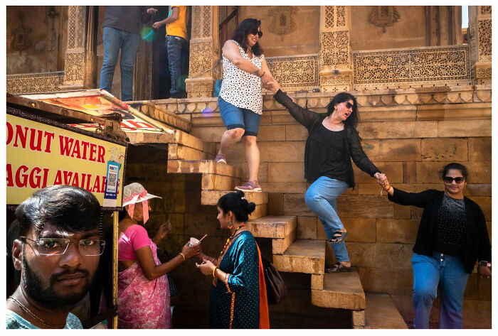 Street photography by Andrés Ramos capturing women descending steps and lively street interactions.