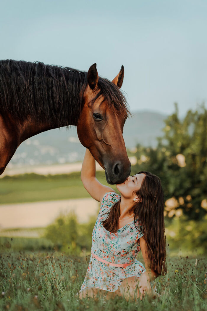 Woman and horse sharing a tender moment in a field, highlighting the special bond between animals and their humans.