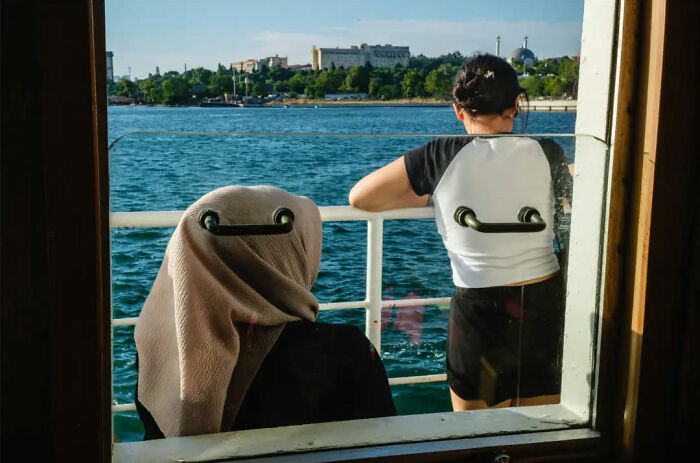 Belgian photographer captures an absurdly amusing scene of two people on a boat with seat faces.