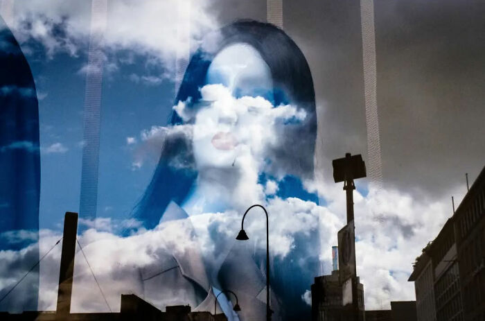 Reflection art of clouds over a woman's face, symbolizing the absurd human condition captured by a Belgian photographer.