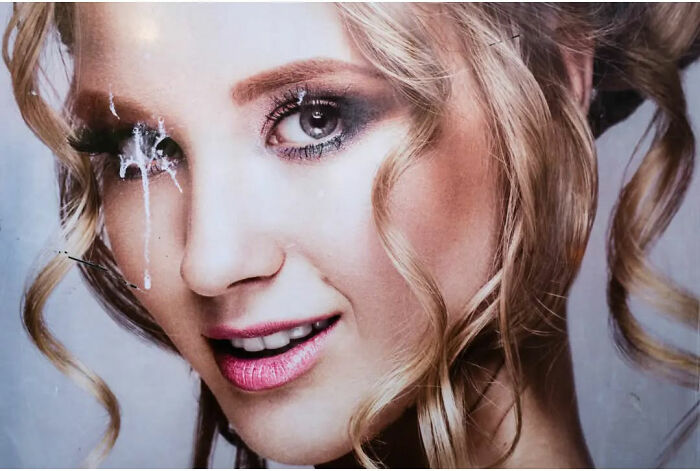 A portrait with paint splatter emphasizes the absurd human condition through unexpected creativity.