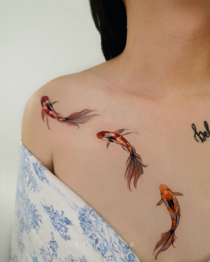 Fine-line tattoos of koi fish on a shoulder, showcasing intricate and dreamy designs.