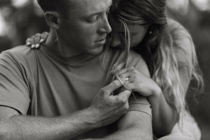 A couple sharing an intimate moment, with focus on an engagement ring, symbolizing 2025's best engagement photos.