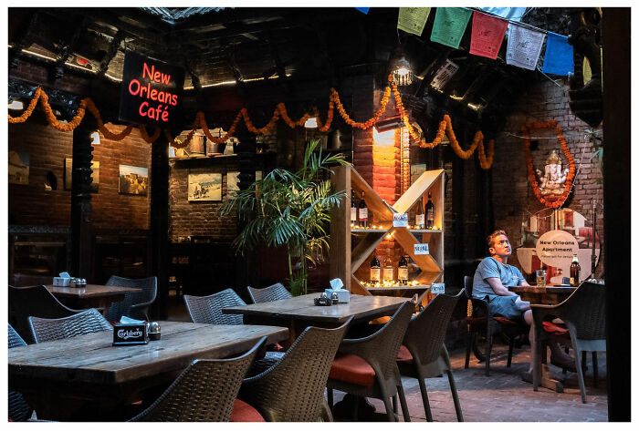 A man sits alone at a table in the New Orleans Café, capturing a raw, unfiltered street moment.