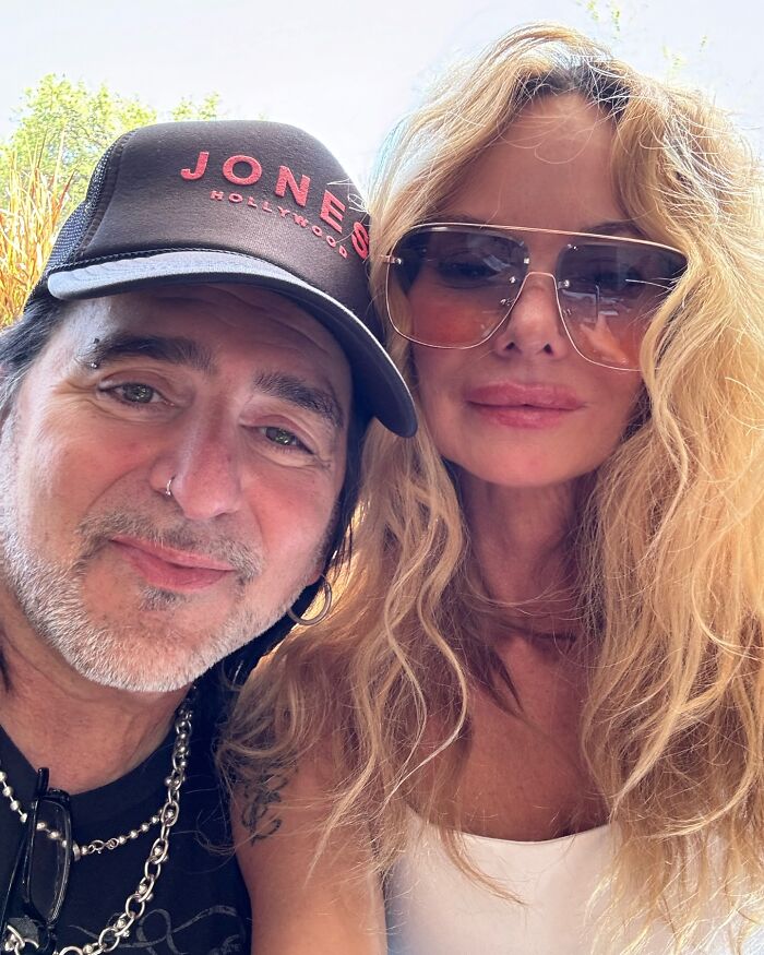 Two individuals smiling outdoors, one wearing a hat, capturing a moment amid reports of a toxic relationship. Two individuals smiling outdoors, one wearing a hat, capturing a moment amid reports of a toxic relationship.