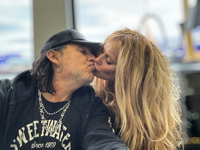 A couple kissing at an indoor setting, featuring glam metal style and jewelry. A couple kissing at an indoor setting, featuring glam metal style and jewelry.