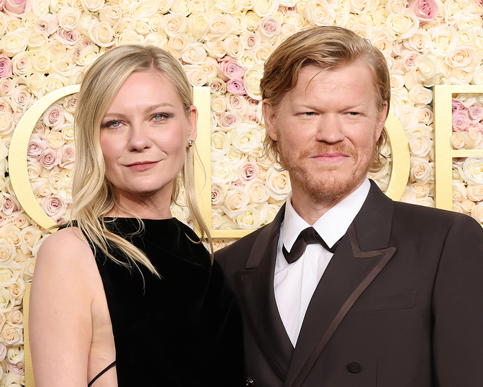 Kirsten Dunst and Jesse Plemons posing together in formal attire against a floral backdrop.